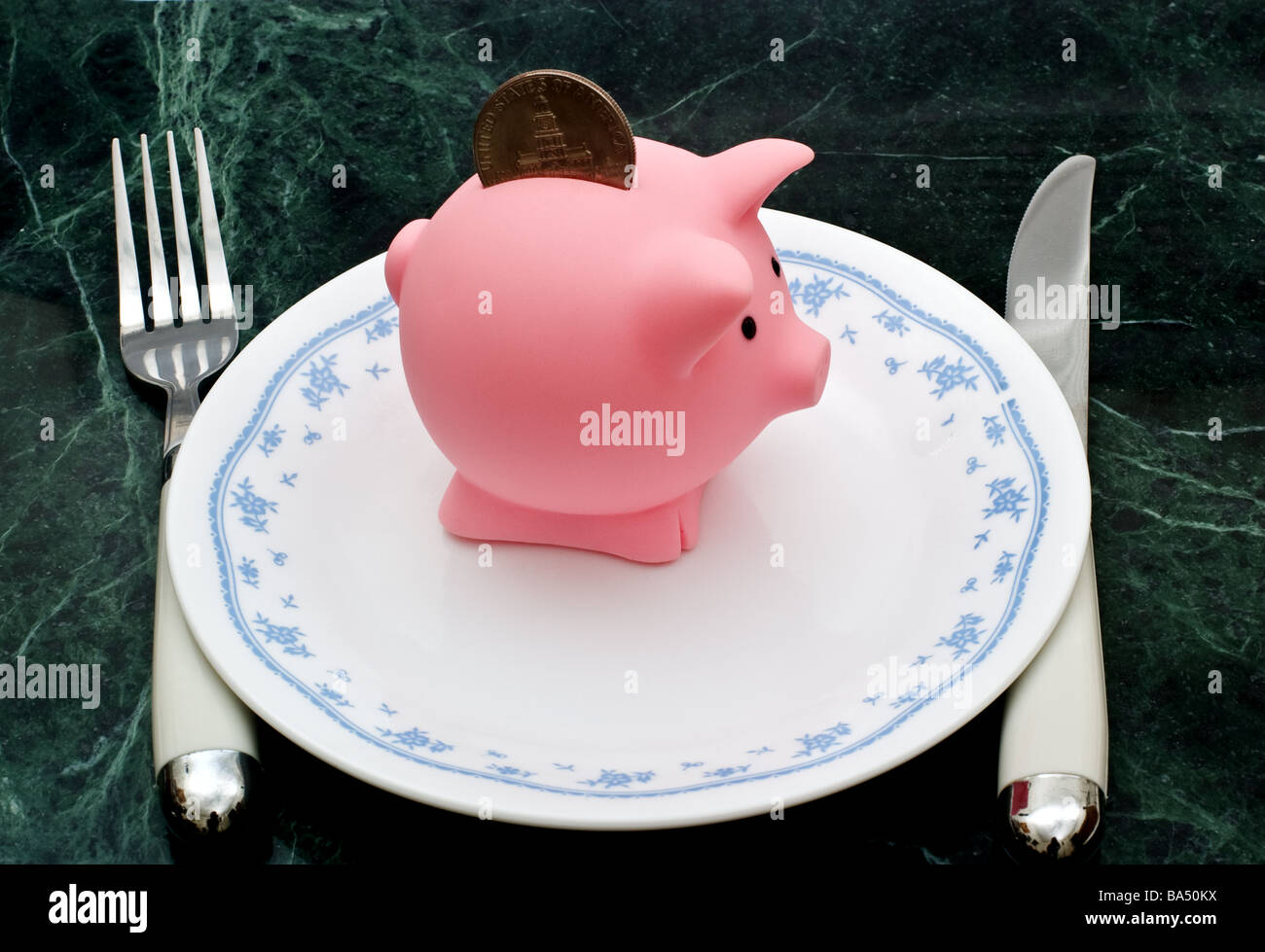 Piccolo salvadanaio con un mezzo dollaro moneta su una piastra con coltello e forchetta Foto Stock