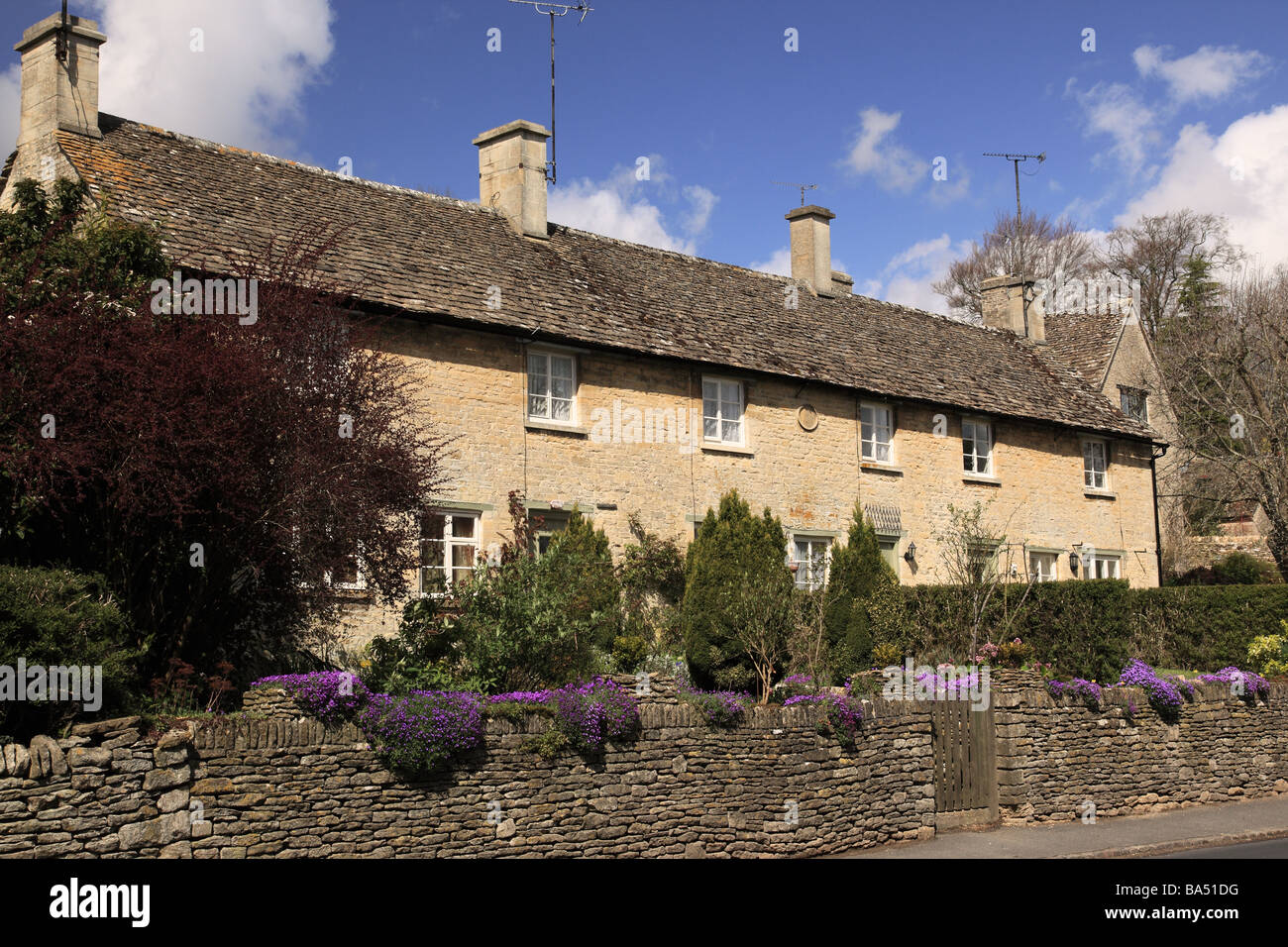 Fila di cottage in pietra a schiera a Barnsley, il Cotswolds, Gloucestershire, Regno Unito in primavera Foto Stock