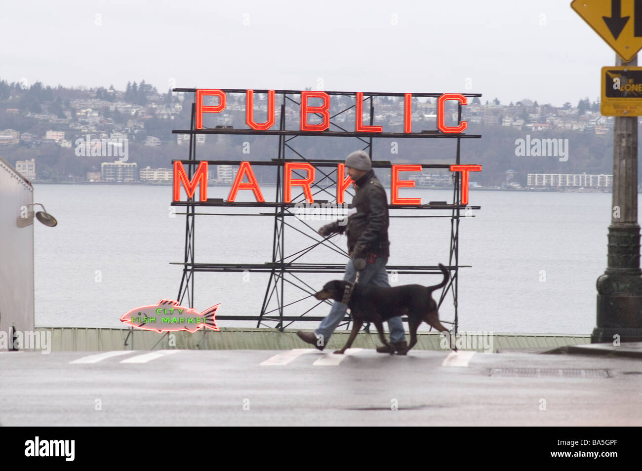 Seattle piove First Avenue con il Pike Place Farmers Market segno e Elliot Bay con passeggiate pedonali cane Foto Stock