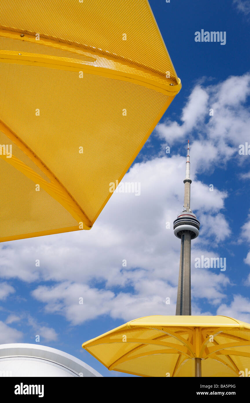 Due metallo giallo ombrelloni in spiaggia urbana di hto park con la CN Tower e il Rogers Centre skydome Foto Stock