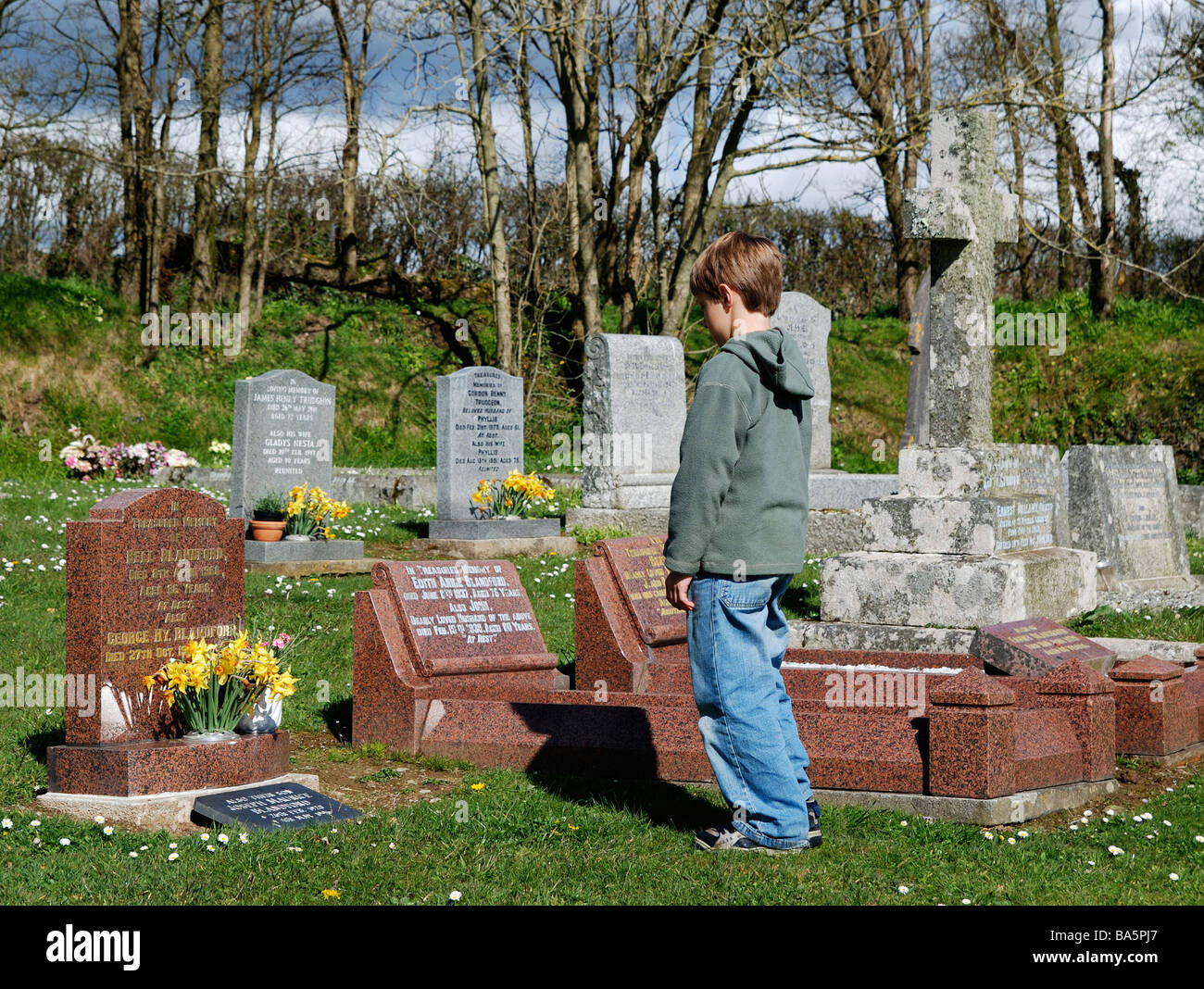 Un piccolo ragazzo al graveside in un cimitero in Inghilterra, Regno Unito Foto Stock