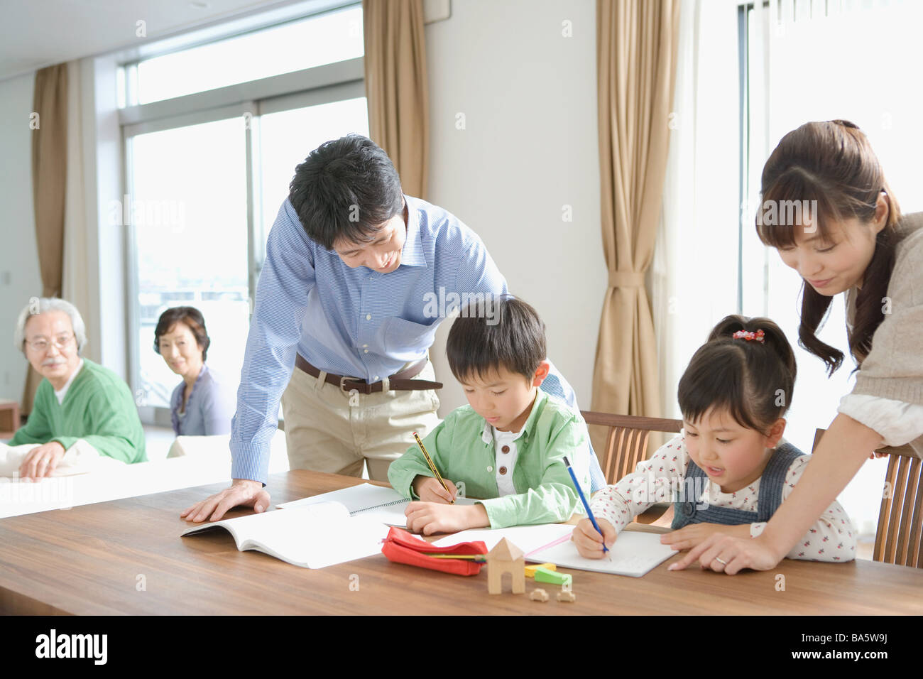 I bambini a fare i compiti di scuola con i loro genitori Foto Stock