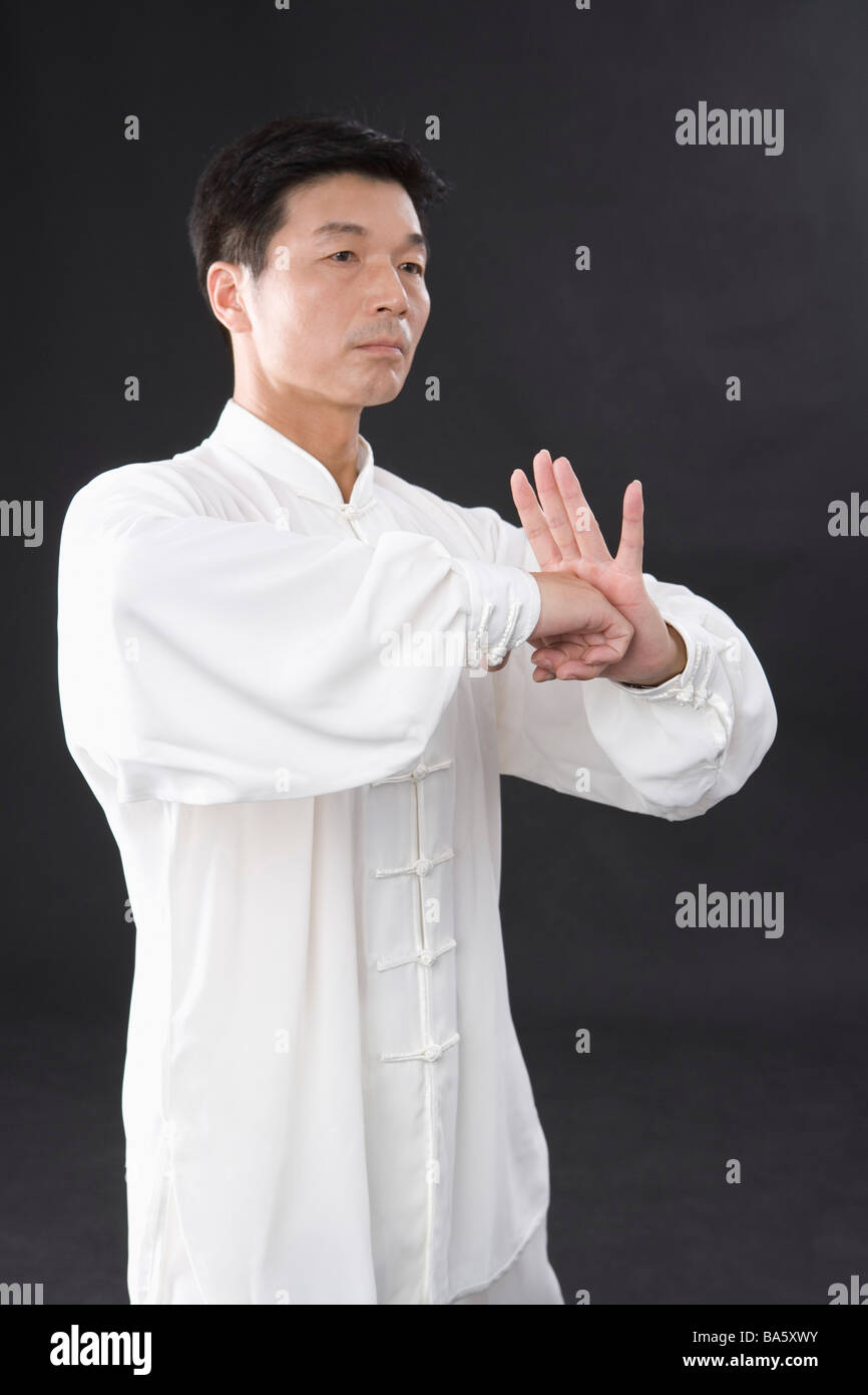 L'uomo praticare il Tai Chi su sfondo nero Foto Stock