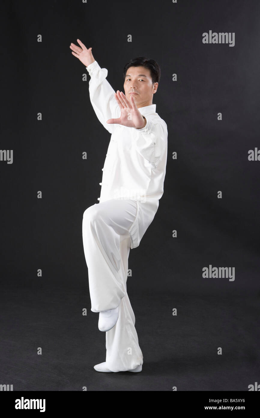 L'uomo praticare il Tai Chi in sfondo nero Foto Stock