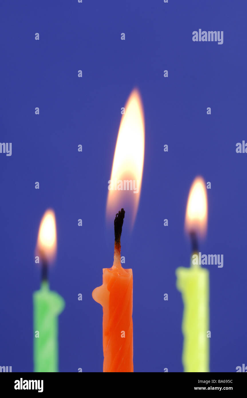 Tre candele differentemente colorato serie ustioni candele di cera compleanno-candele colorfully colorato di arancione giallo verde fiamme Foto Stock
