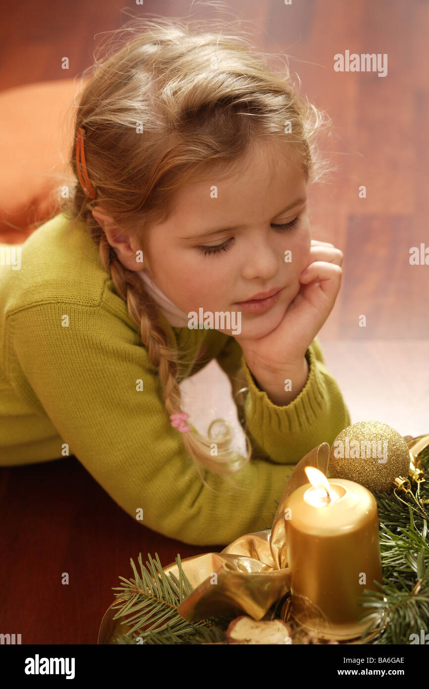 Ragazze piano giacciono head sguardo Avvento-corona poggia candela brucia ritratto persone bambino-ritratto INFANZIA 7-8 ANNI bionda Foto Stock