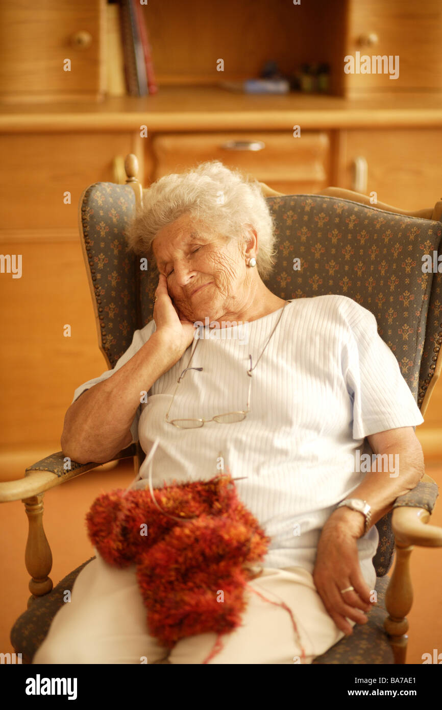 Sale di soggiorno senior sedie siede maglia si addormenta dettaglio serie persone anziani donna 70-80 anni grigio-bianco dai capelli dai capelli Foto Stock