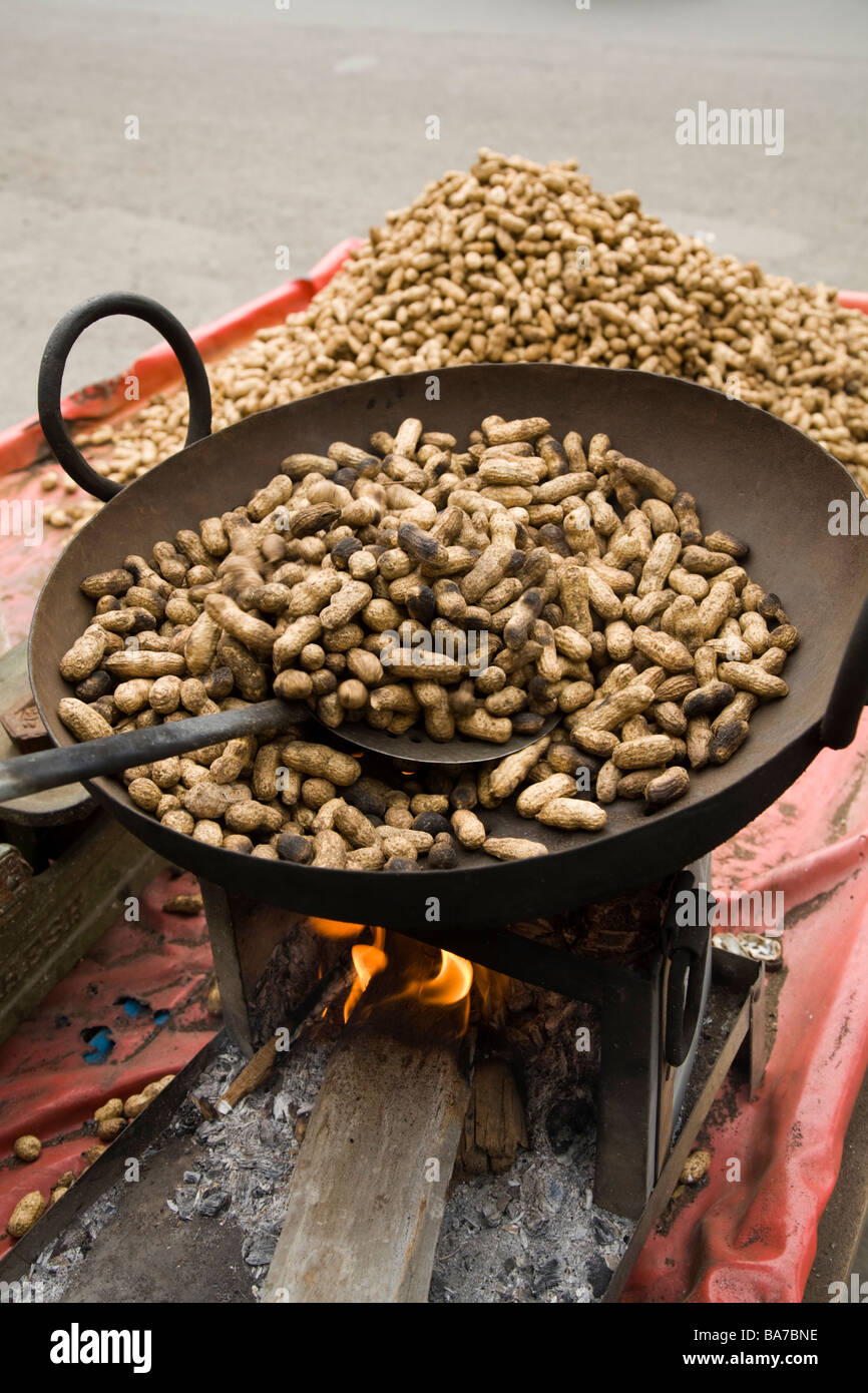Venditore ambulante di arachidi tostatura su un bruciatore aperta e la loro vendita in Surat. Il Gujarat. India. Foto Stock