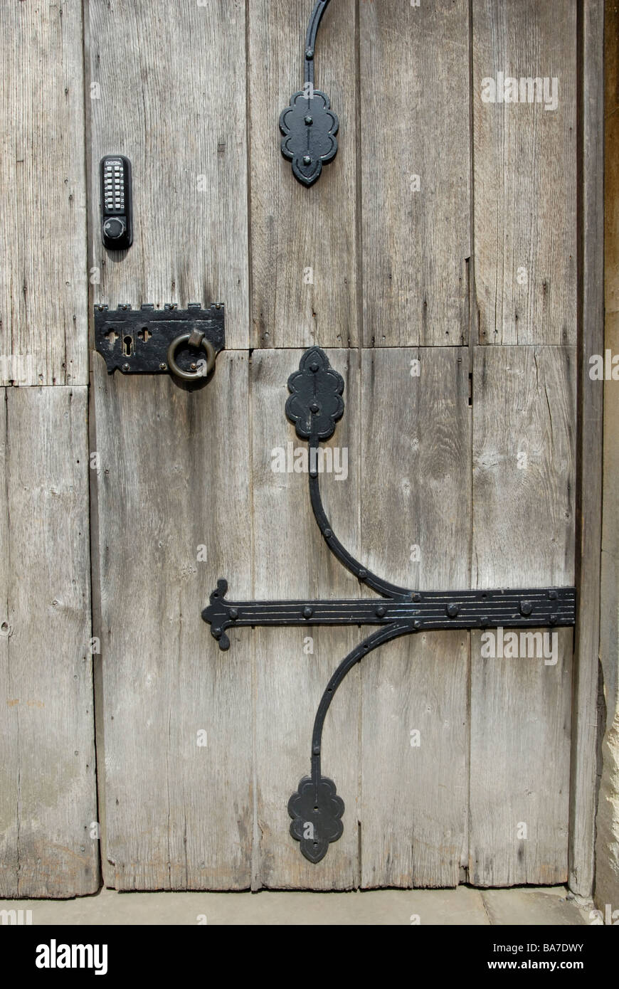 Nuovo digitale pulsante blocco pad a fianco antico sistema di blocco con chiave e ornamentali in ferro battuto delle cerniere sul weathered porta della chiesa Foto Stock