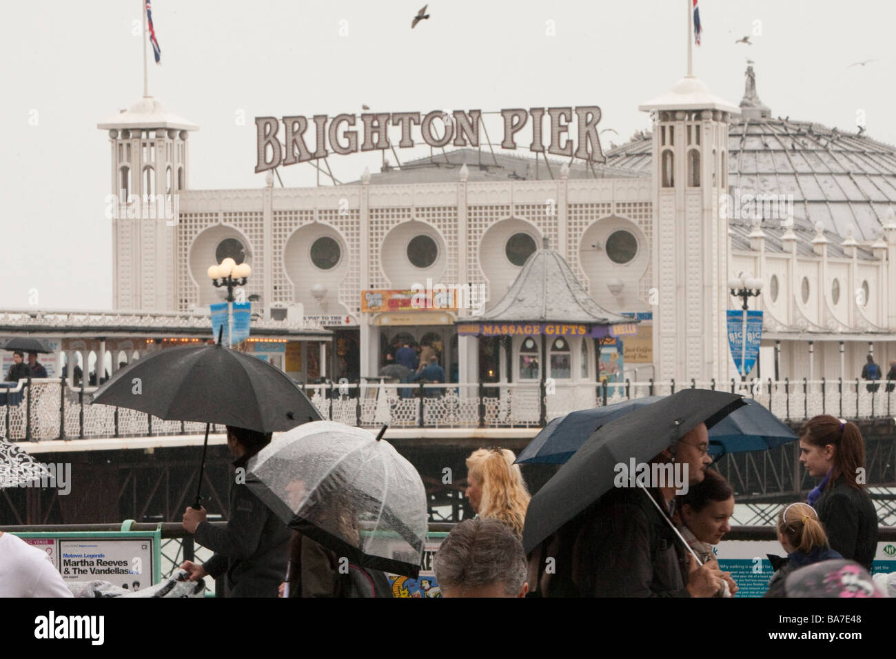 Persone in heavy rain con ombrelloni, il Palace Pier, Brighton Foto Stock