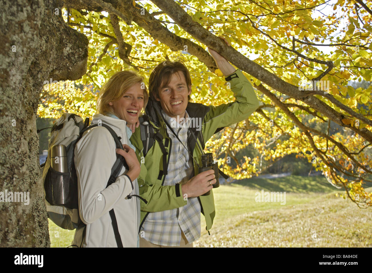 Compagno di Escursionismo autumn tree resto binocolo sorrisi semi-portrait 30-40 anni attività di Outlook di viaggio al di fuori del registro ad albero osserva Foto Stock