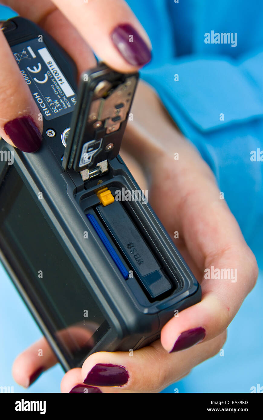 Ragazza fotocamera digitale compatta che mostra la batteria e chip di memoria della scheda di memoria | dito Batterie Chipkarte digitale Kompakt Kamera Foto Stock
