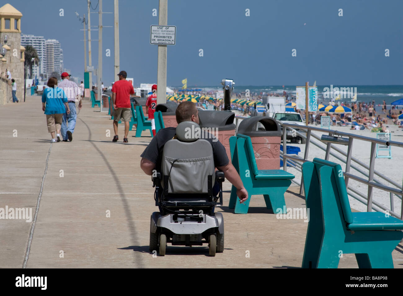 Persona con handicap a ruote lungo la spiaggia in una località turistica per visitare i siti turistici e giornata di sole. Foto Stock