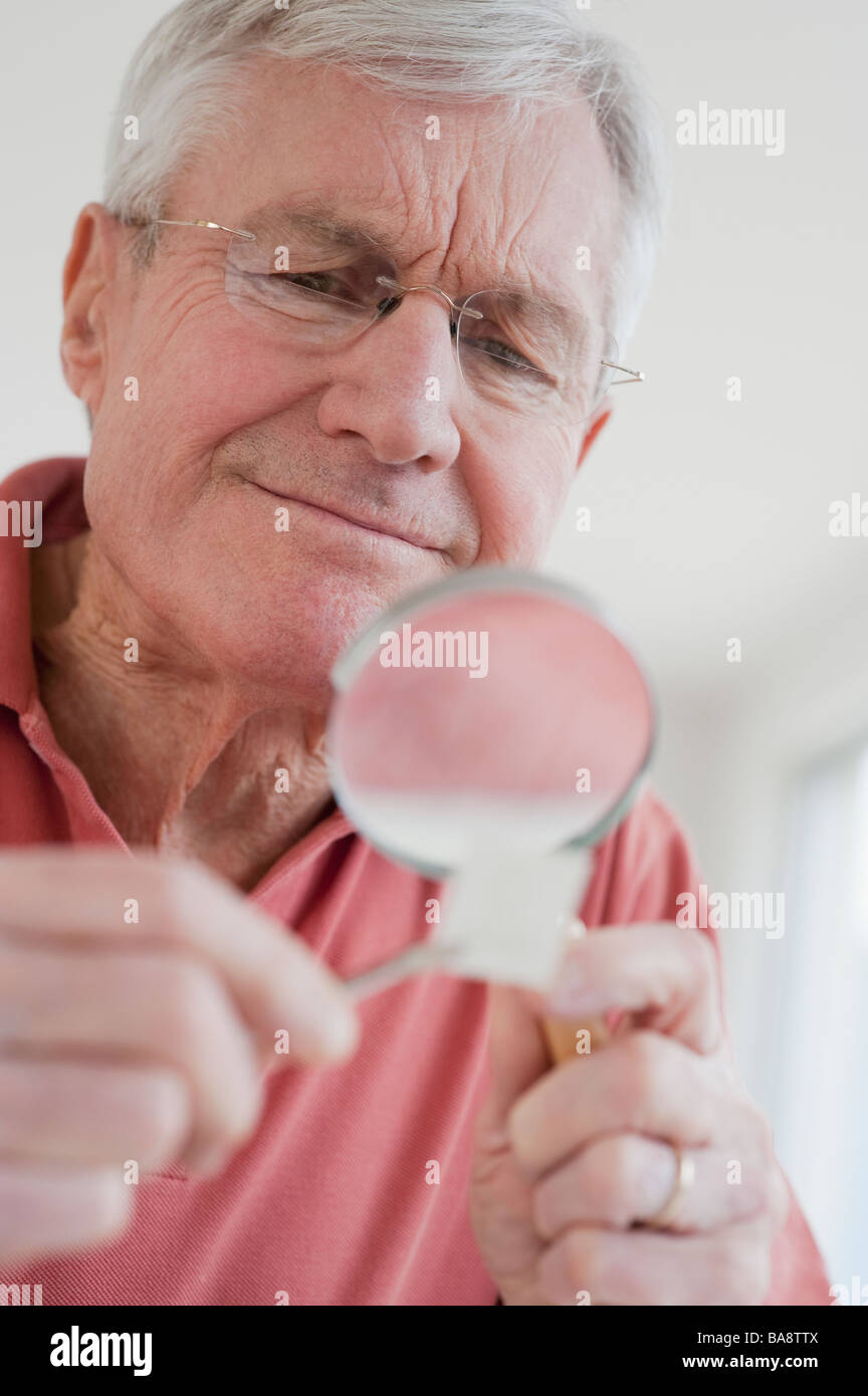 Senior uomo guardando alla raccolta di francobolli Foto Stock