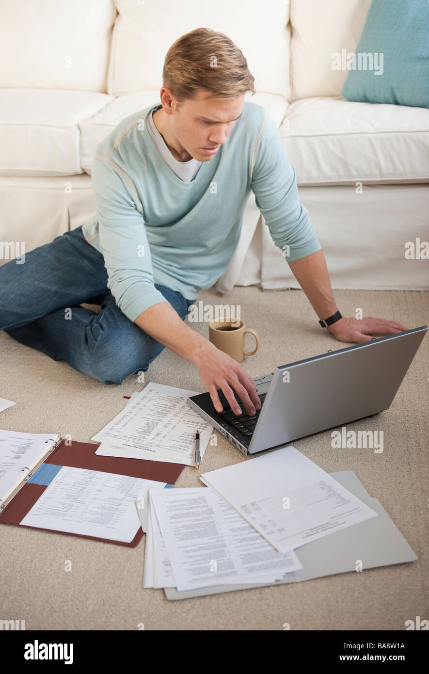 Uomo al lavoro su laptop in livingroom Foto Stock