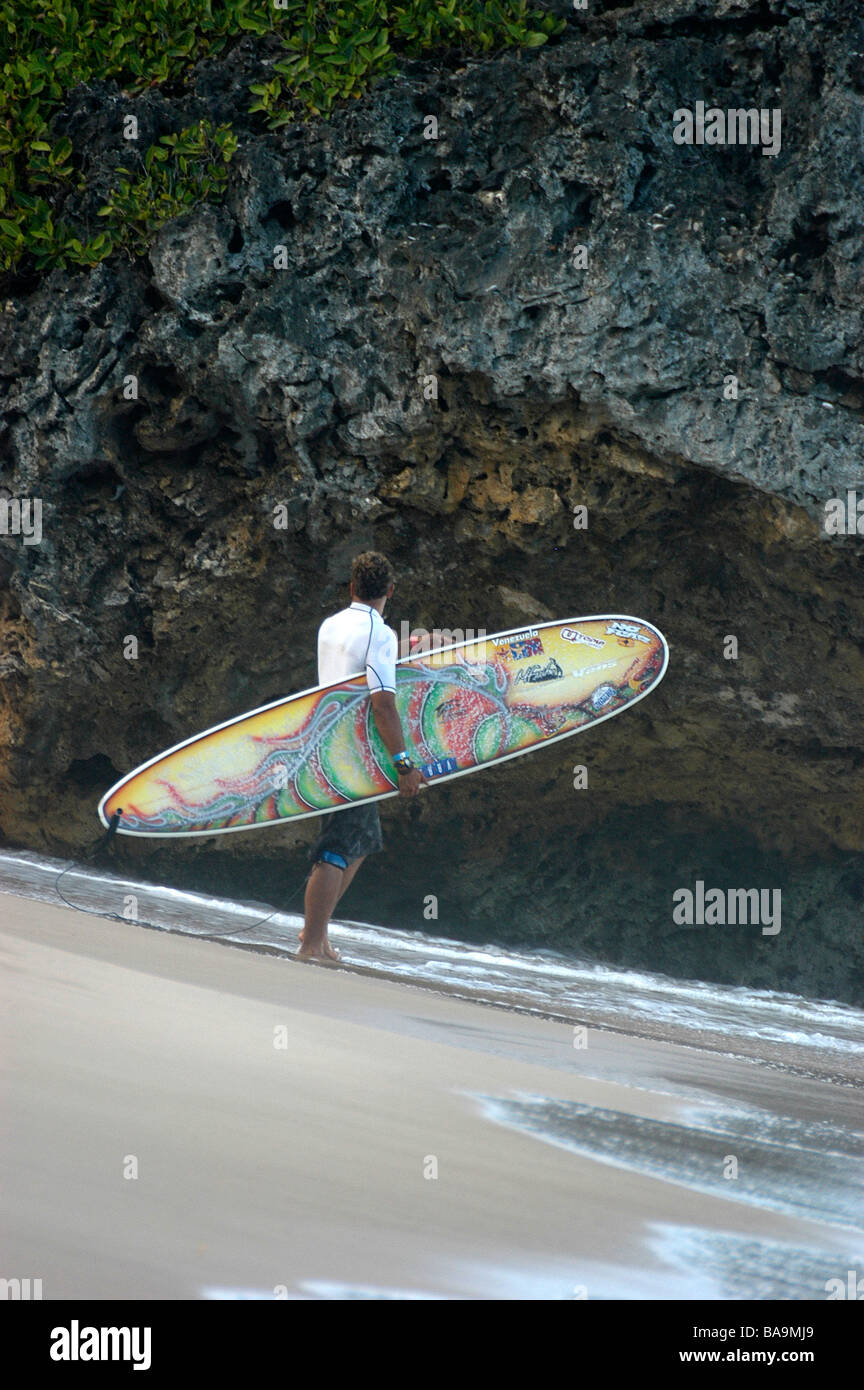Un surfista mantiene la sua tavola da surf prima di entrare in mare per il surf Foto Stock