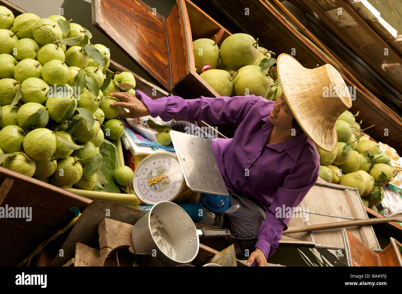 Un Thai fruttivendola preleva un apple dal suo stallo in barca al mercato galleggiante vicino a Bangkok in Tailandia Foto Stock