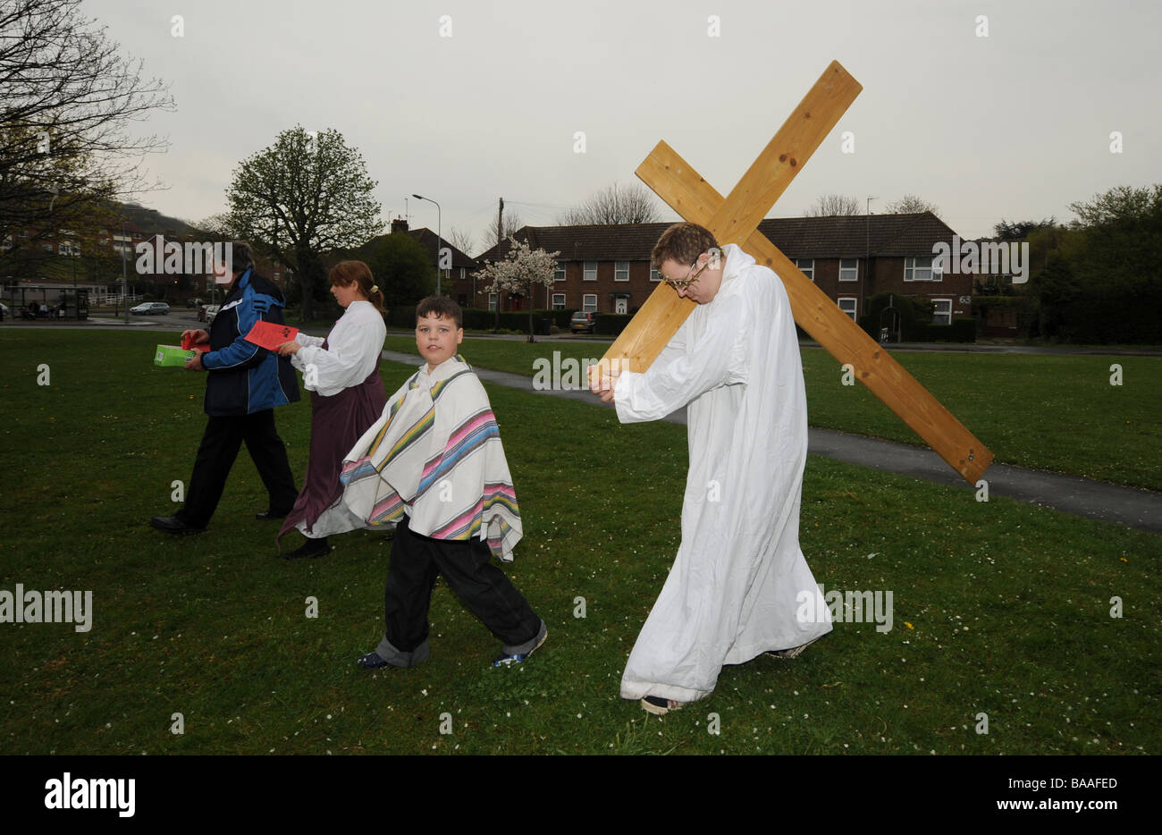 Un adolescente porta una croce sulle spalle come egli gioca la parte di Gesù in una nuova promulgazione della Passione il servizio sul Venerdì Santo Foto Stock