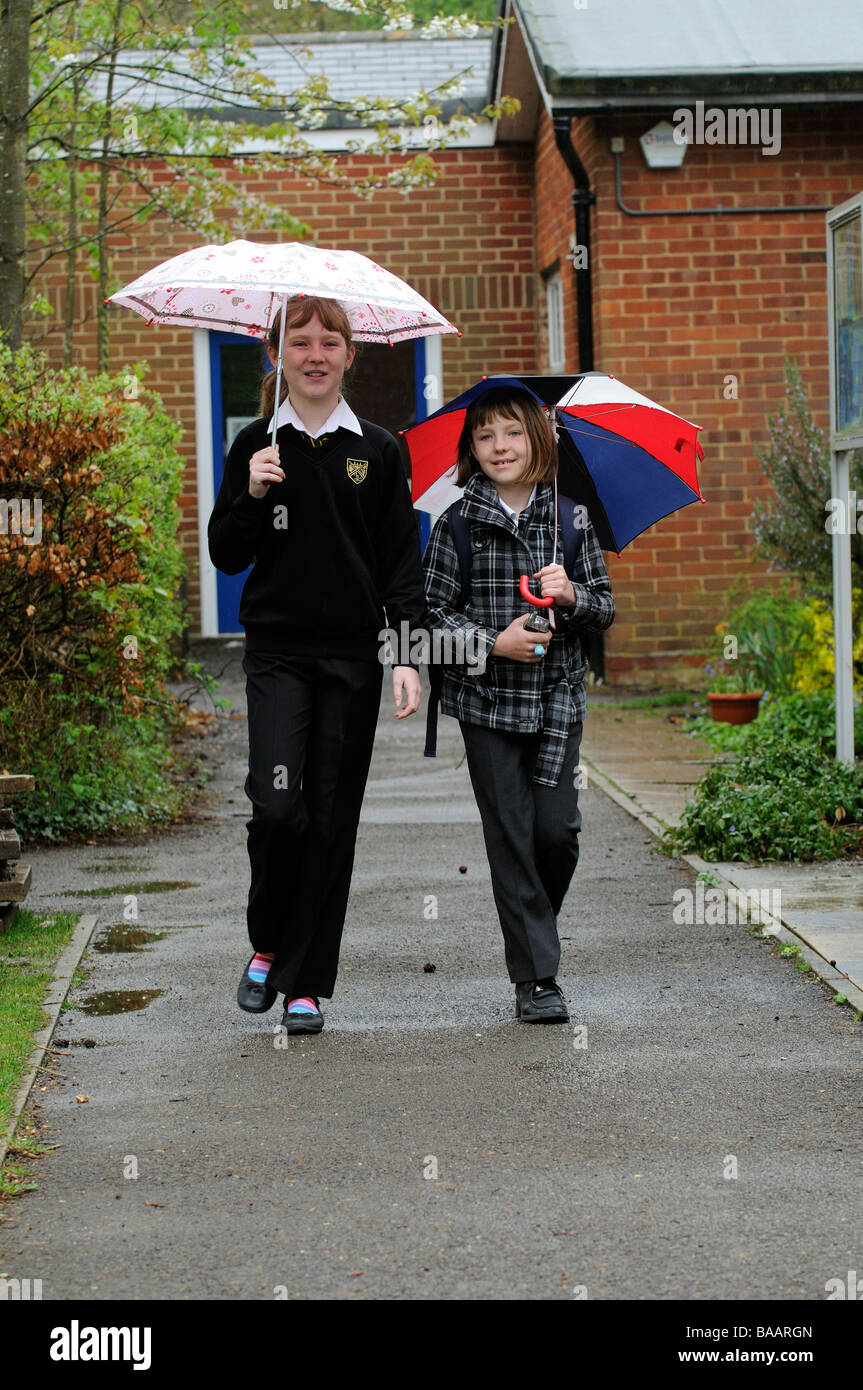 I bambini a piedi dalla scuola sotto la pioggia Foto Stock