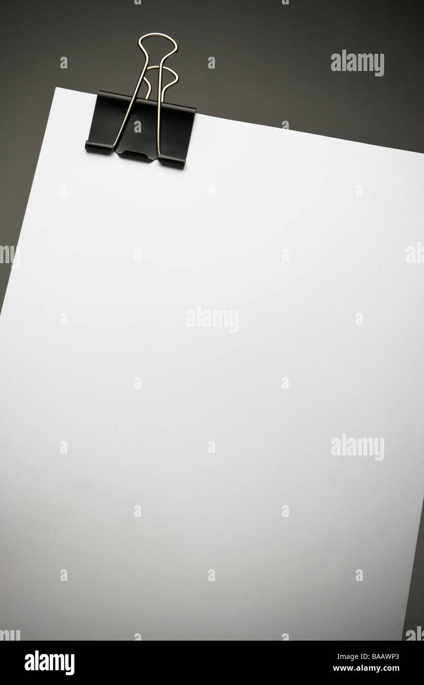 Libro bianco e nero grande clip legante sul bordo superiore contro sfondo grigio scuro con vignette shadow, composizione verticale Foto Stock