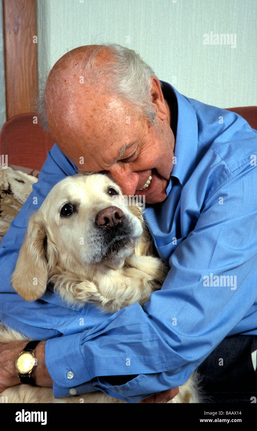 Uomo anziano coccole pet il suo golden retriever cane Foto Stock