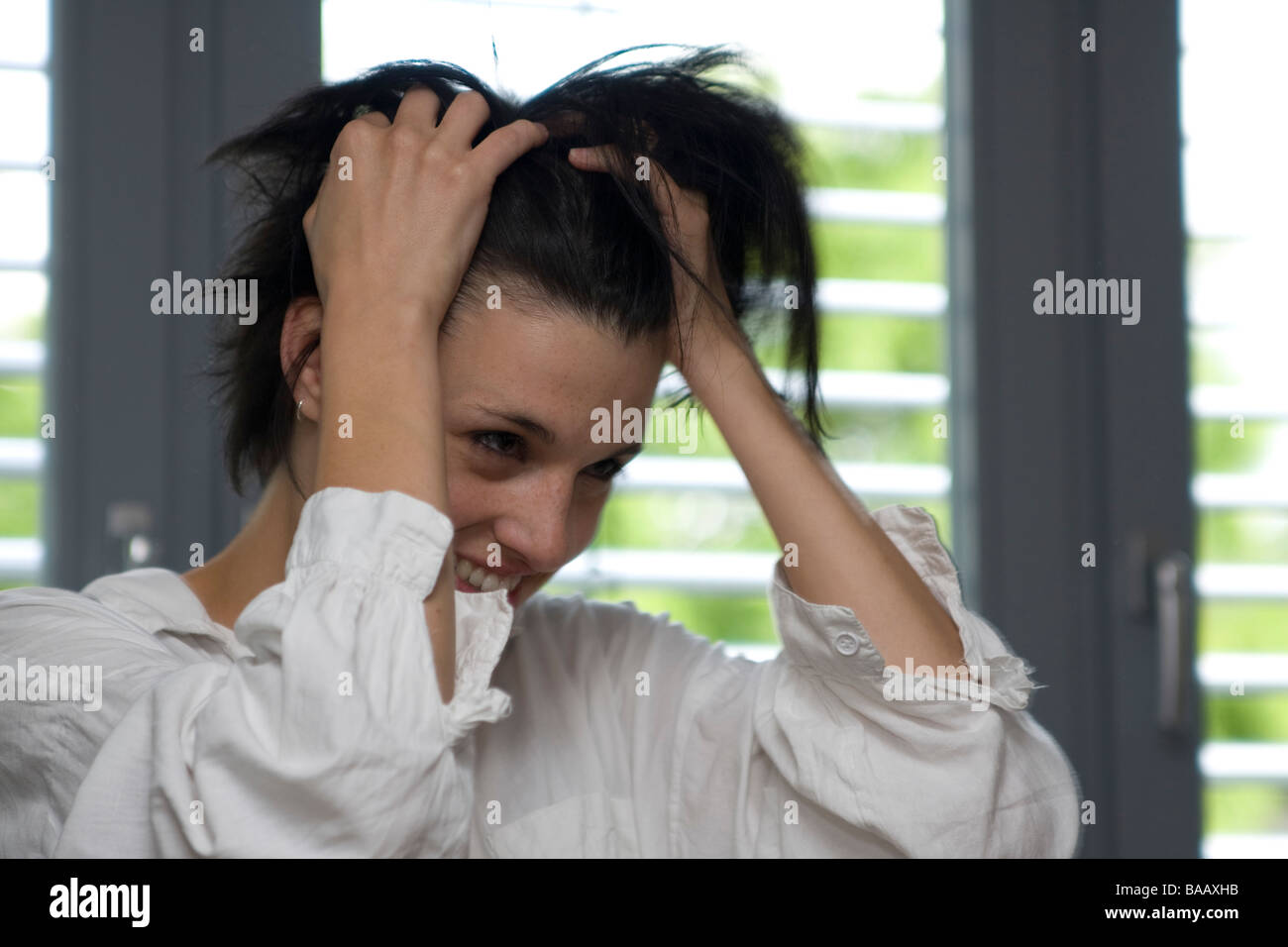 Giovane donna eseguire le dita attraverso i suoi capelli - Junge Frau fährt sich mit den Fingern durch die Haare Foto Stock