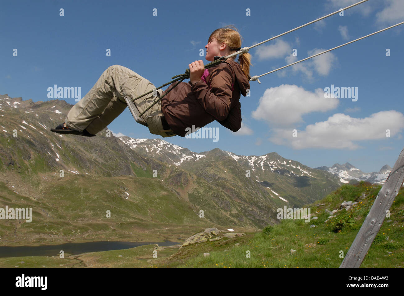 Donna su un altalena con montagne in lui sfondo, Sedrun, Svizzera Foto Stock