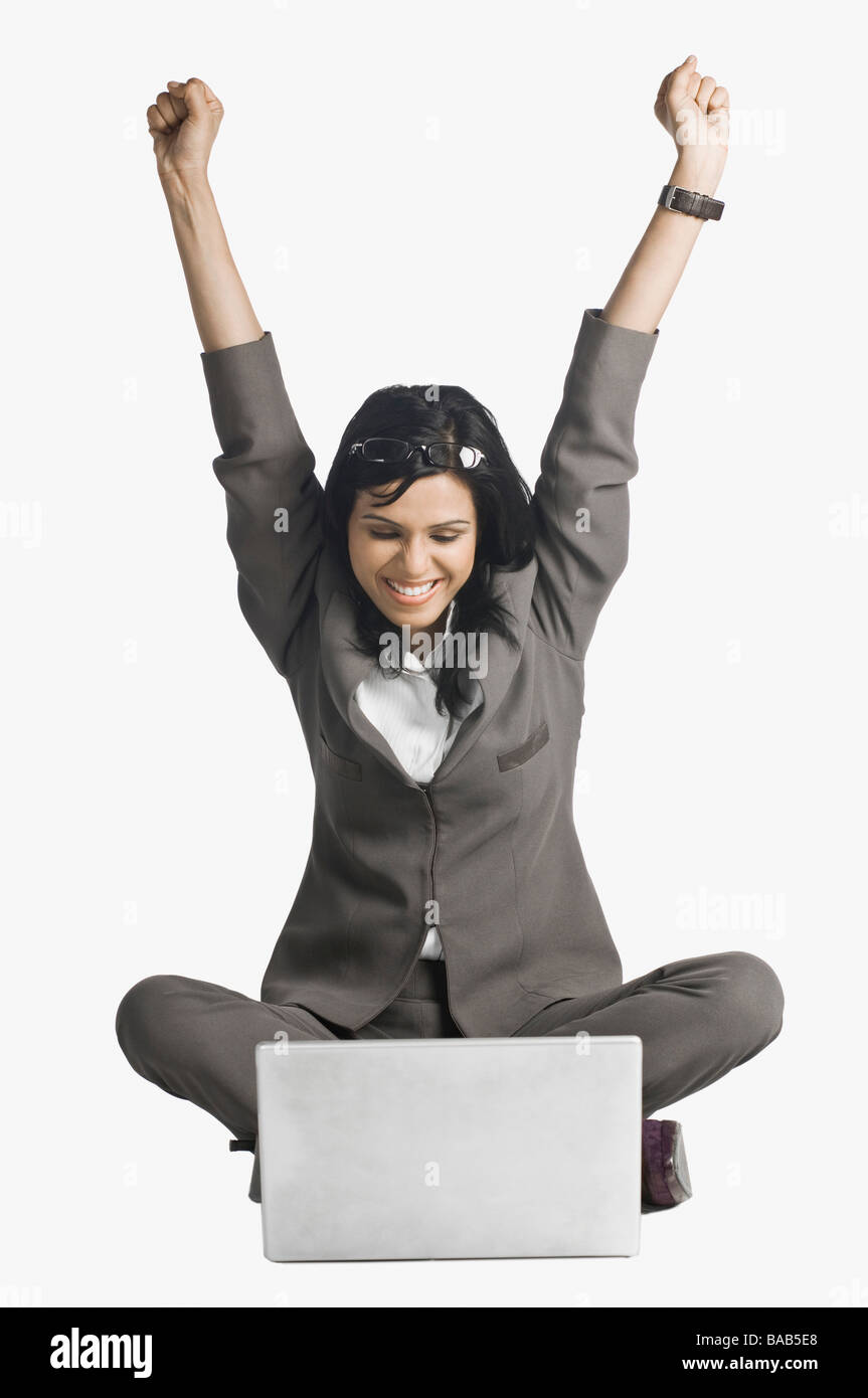 Donna sorridente con le braccia sollevate nella parte anteriore di un laptop Foto Stock