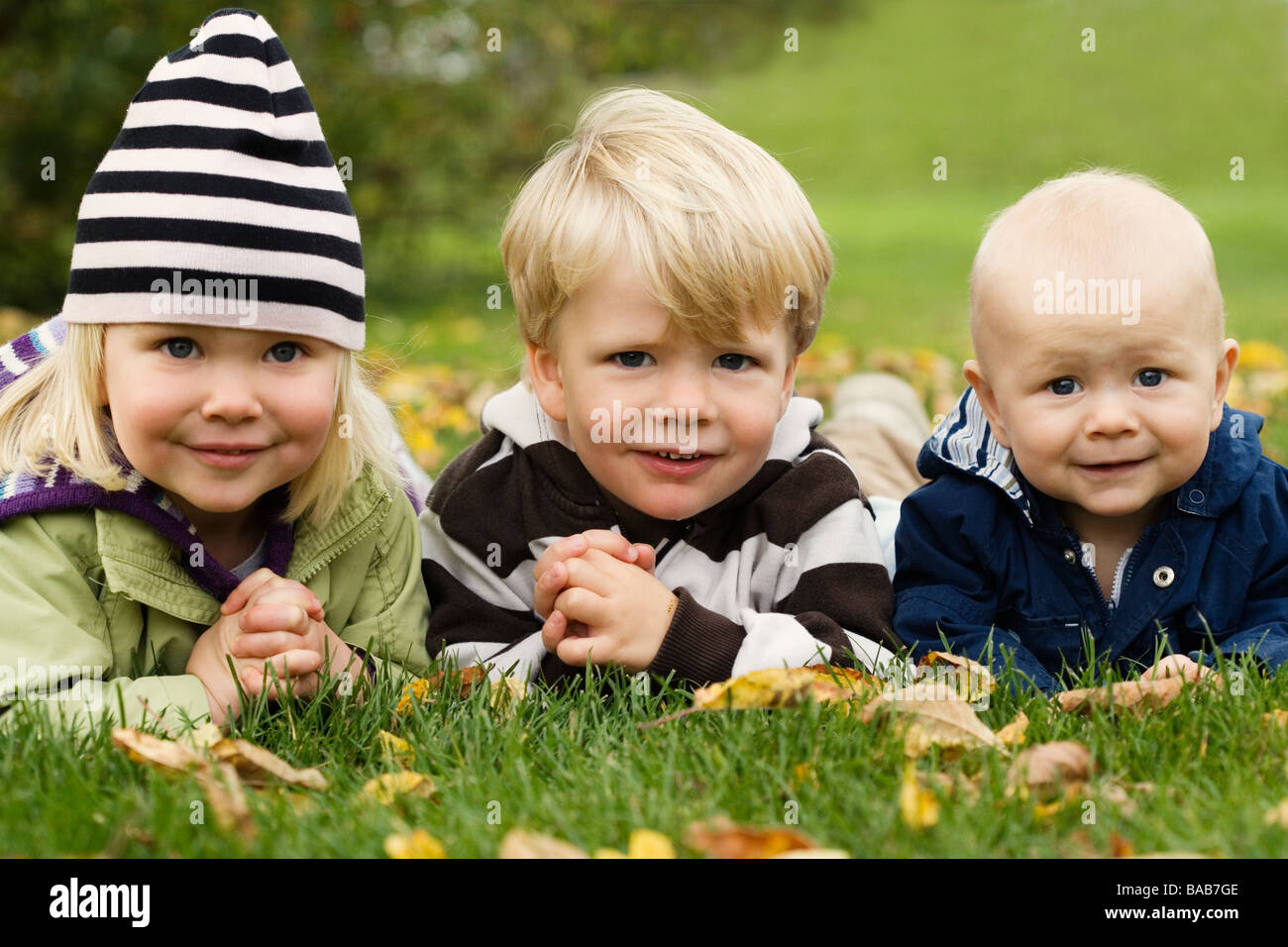 Tre bambini sdraiati su un prato, Nacka, Svezia. Foto Stock