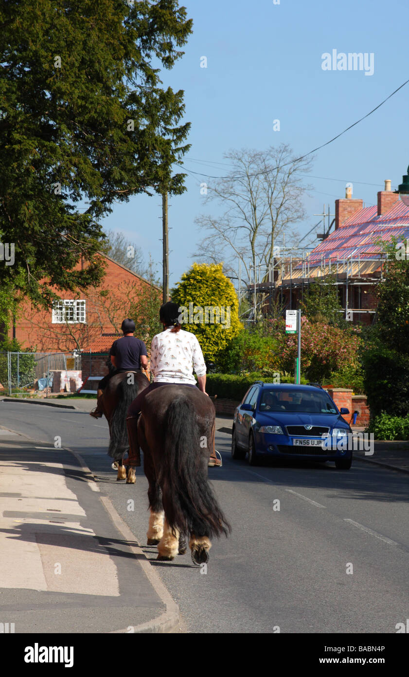 Cavalli su una strada del villaggio con il passaggio del traffico. Foto Stock