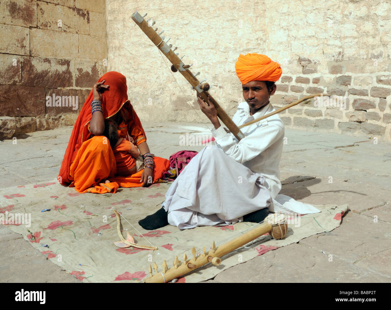 Un musicista in un turban arancione riproduce una chitarra in un cortile di Meherangarh, Foto Stock