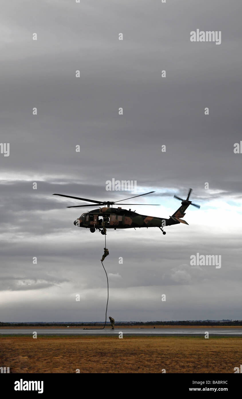 Australian l esercito lo scorrimento verso il basso una corda da un Black Hawk elicottero Foto Stock