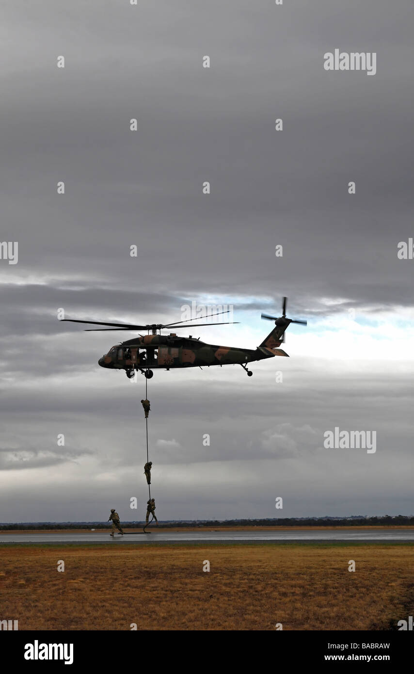 Australian l esercito lo scorrimento verso il basso una corda da un Black Hawk elicottero Foto Stock