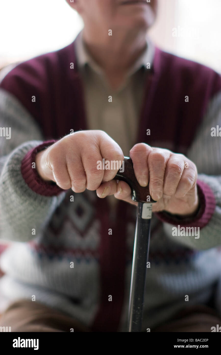 Uomo anziano oap vecchiaia titolare di pensione o di rendita delle mani che impugnano un bastone a casa Foto Stock