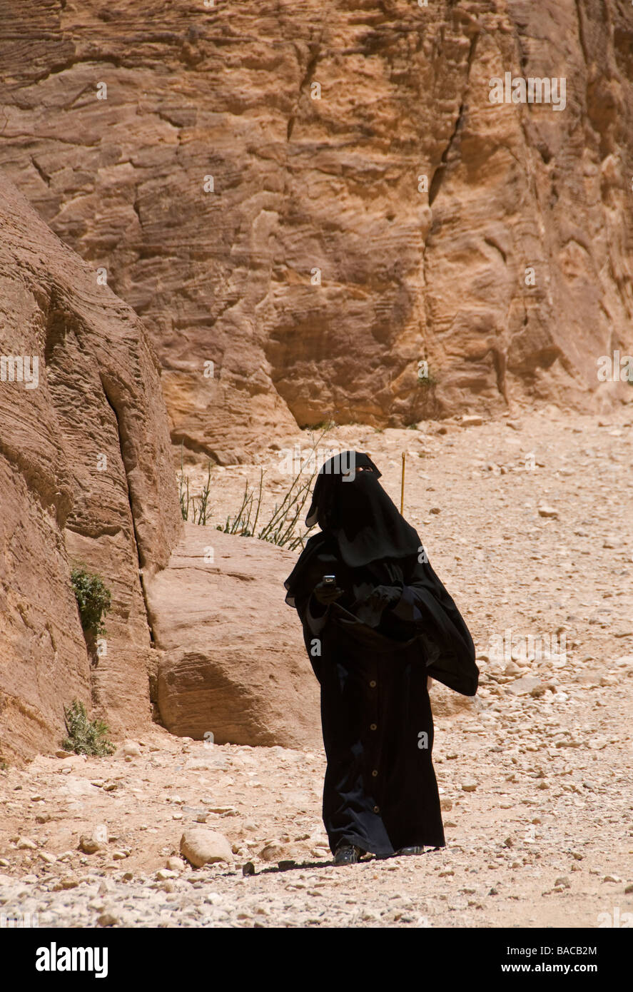 Un beduino donna che indossa un nero panno Niqab vagare all'antica Nabatean città di Petra in Giordania Foto Stock