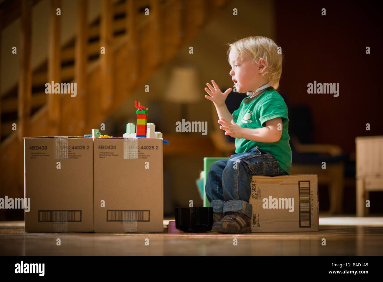 Il Toddler dicendo Mom utilizzando il linguaggio dei segni durante la riproduzione con giocattoli su scatole di cartone Foto Stock