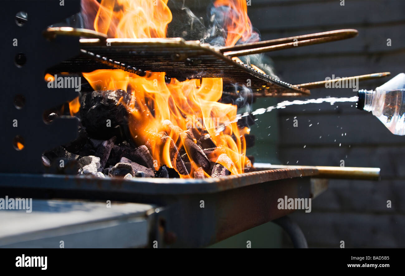 Illuminazione di schizzamento carburante fluido su un carbone Bar-B-Q per aumentare le fiamme. Foto Stock