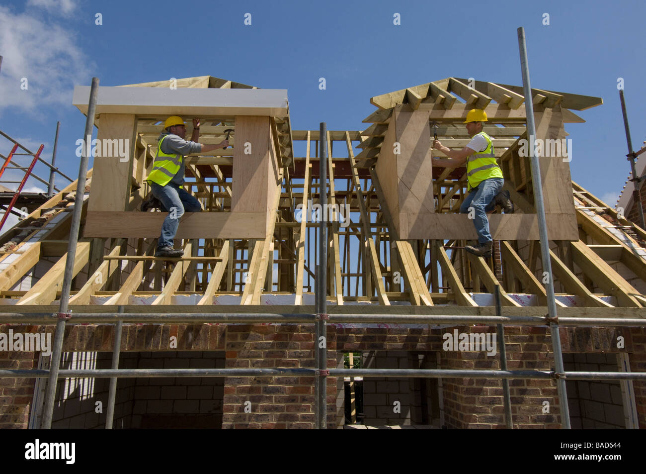Costruttori lavorando su finestre dormer sul tetto di una casa nuova. Foto Stock