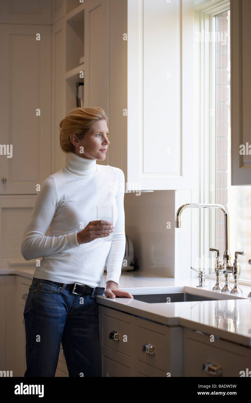 Donna di riempimento in vetro dal rubinetto di cucina Foto Stock