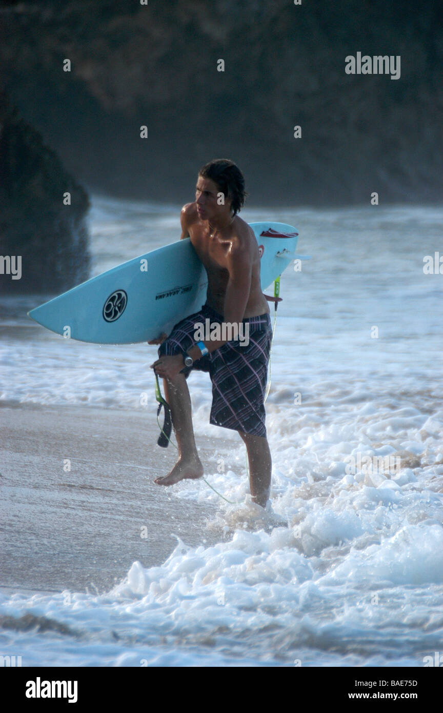 Un surfista si allenta la sua fascetta di surf dopo provenienti dal mare Foto Stock