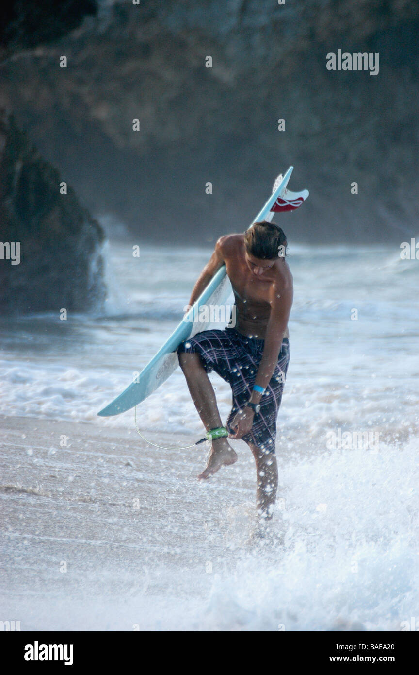 Un surfista si allenta la sua fascetta di surf dopo provenienti dal mare Foto Stock