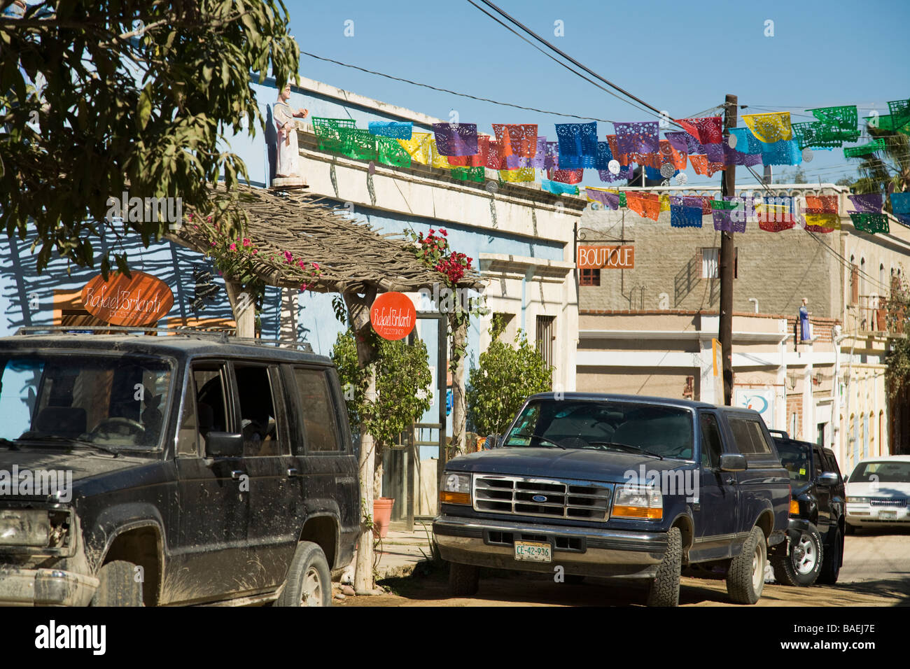 Messico Todos Santos colorati bandiere di carta appeso sopra street nel centro di shop e galleria polveroso distretto camion parcheggiato Foto Stock