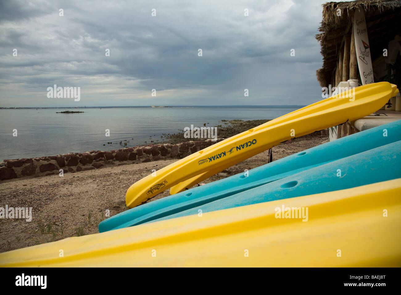 Messico La Paz colorato sedersi sulla sommità kayak ribaltato e appoggiata contro la spiaggia di recinzione lungo la baia Foto Stock