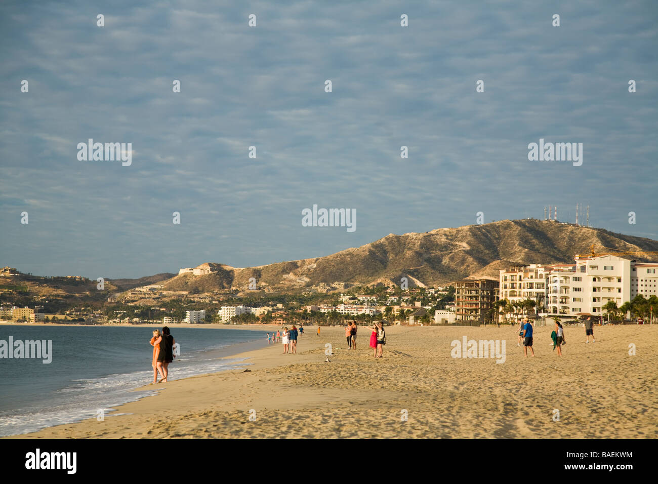 Messico San Jose del Cabo gente camminare e passeggiare lungo la spiaggia di mattina presto edifici sulla collina Foto Stock