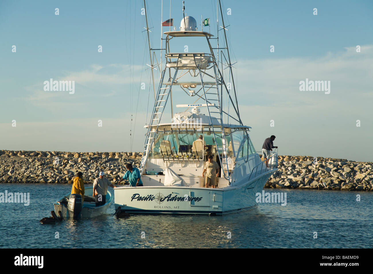 Messico La playita uomini vendita di pesci da esca dal motoscafo accanto alla più grande barca da pesca in porto Foto Stock
