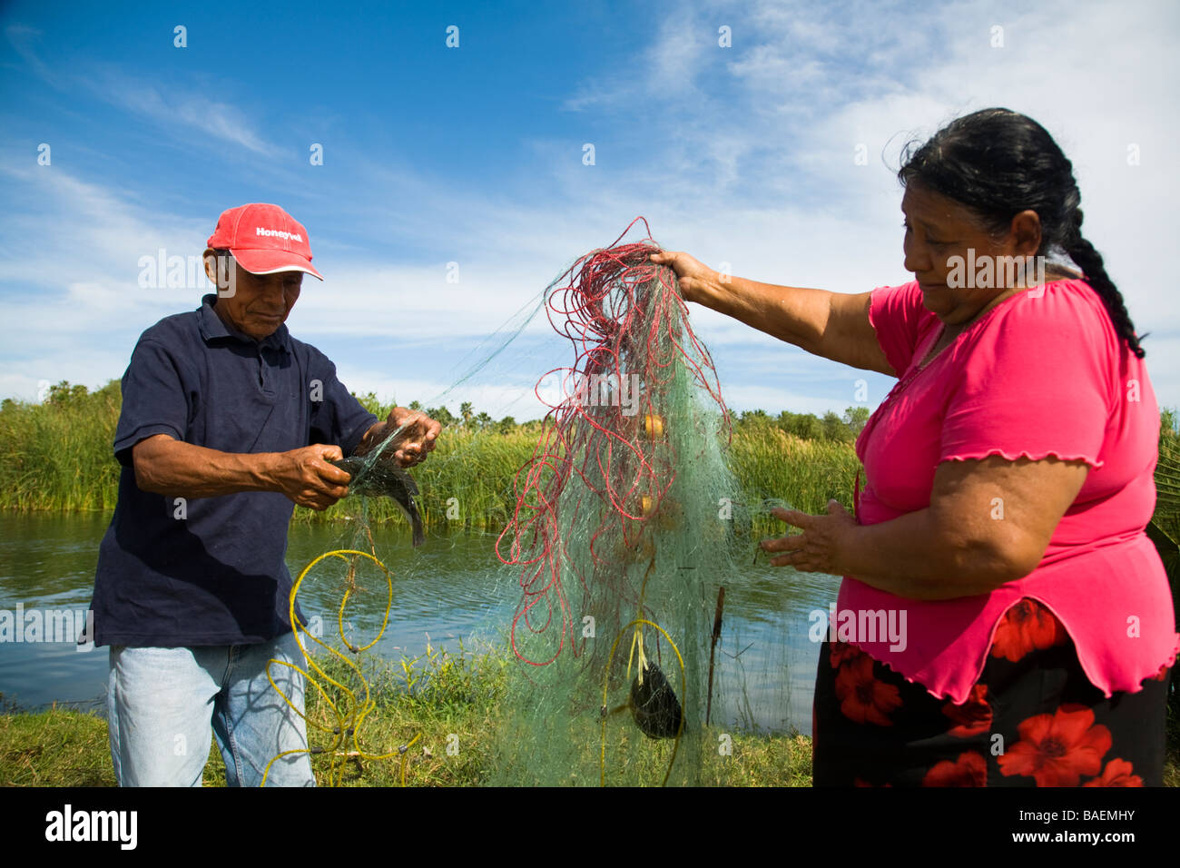 Messico San Jose del Cabo Mexican l uomo e la donna rete di contenimento con pesce pesca nel fiume di acqua dolce che alimenta estuario Foto Stock