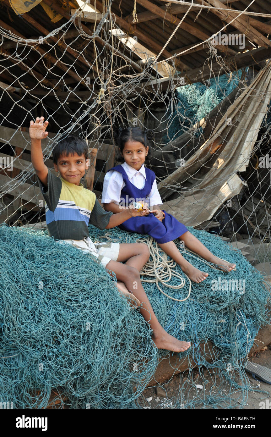 Bambini seduti sulle reti da pesca in Colaba area di Mumbai Foto Stock