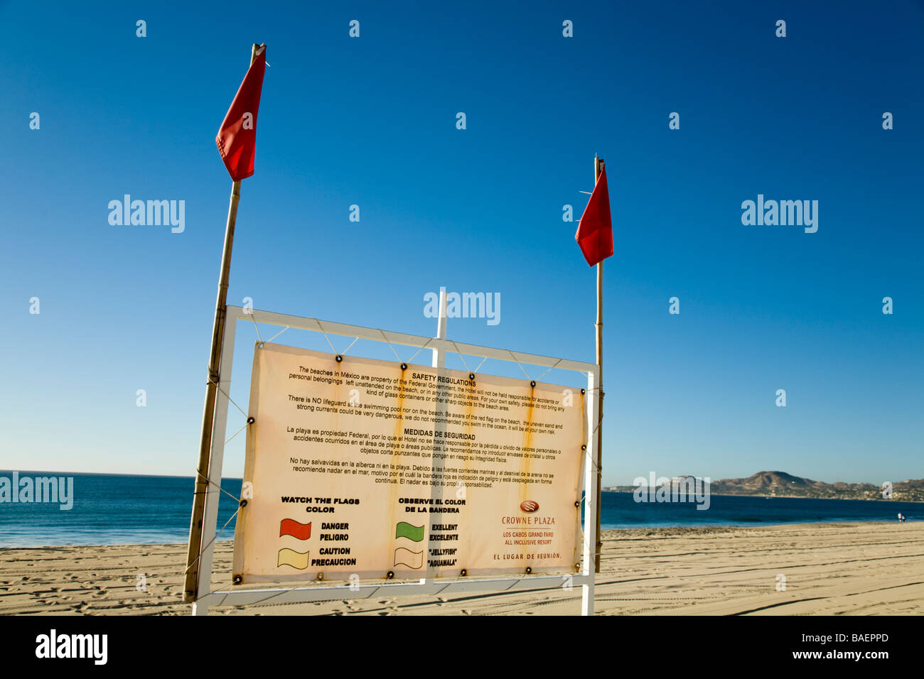 Messico San Jose del Cabo bandiere rosse presso la spiaggia di avvertimento di condizioni pericolose sign in inglese e in spagnolo per spiegare le bandiere Foto Stock