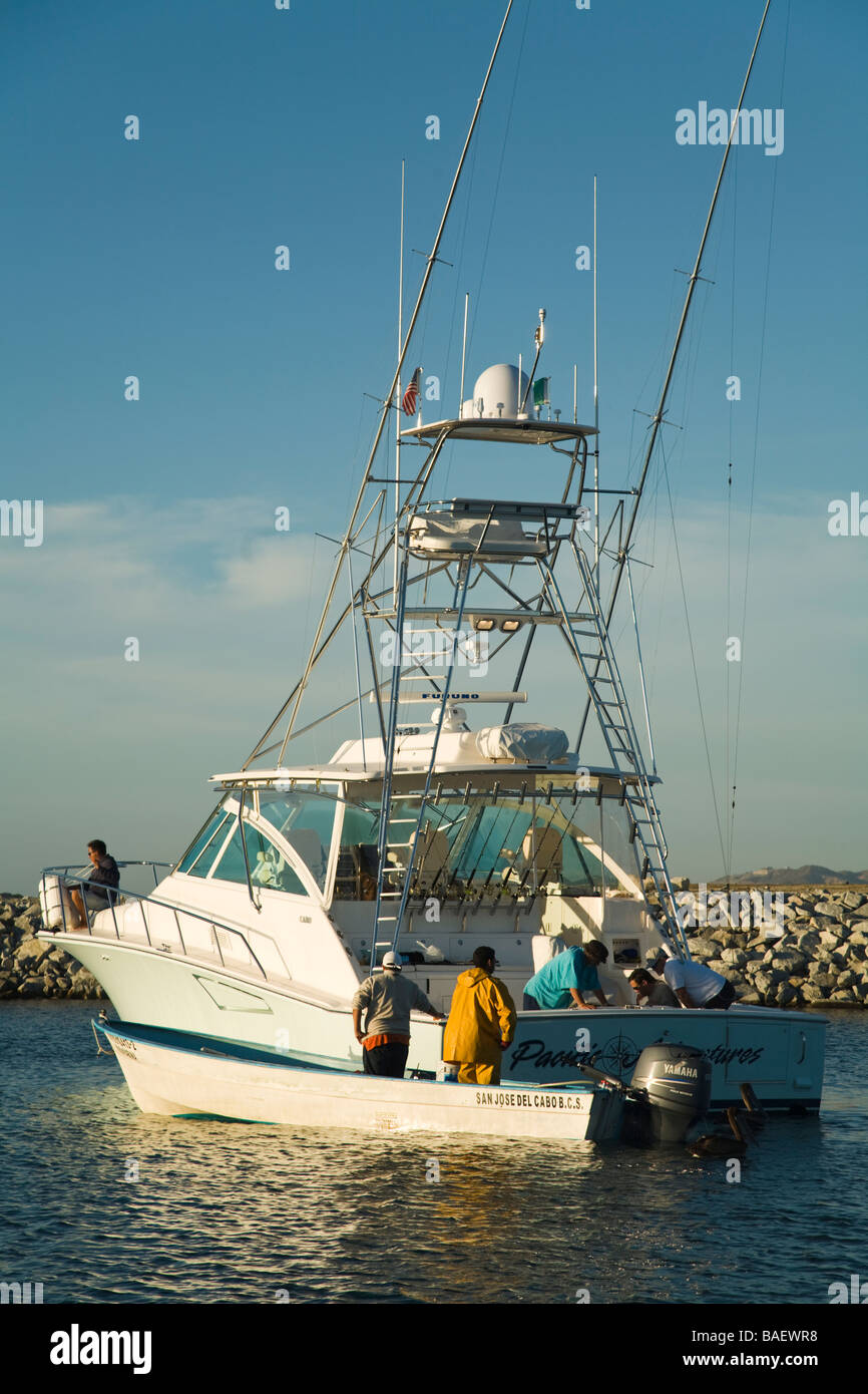 Messico La playita uomini vendita di pesci da esca dal motoscafo accanto alla più grande barca da pesca in porto Foto Stock