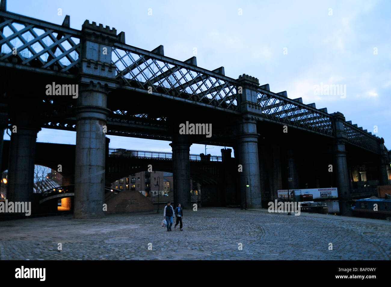 Giovane a piedi dalla storica vecchia ferrovia industriale ponte sopra il Bridgewater Canal,Castlefield,Manchester,sera Foto Stock
